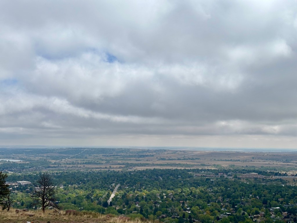 A panoramic view of a lush green landscape with scattered residential areas under a cloudy sky.