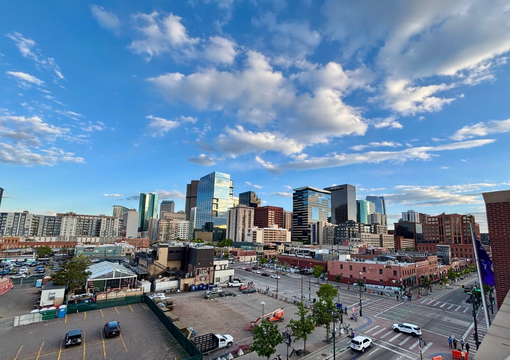Panoramic view of a city skyline featuring modern skyscrapers under a partly cloudy sky.